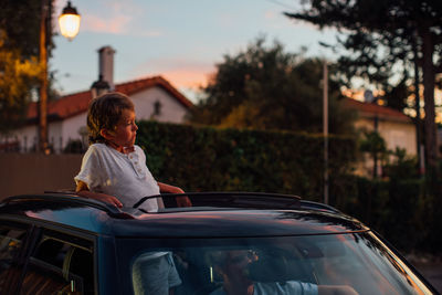 Rear view of boy sitting on car