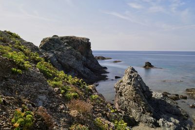 Rock formations on shore against sky