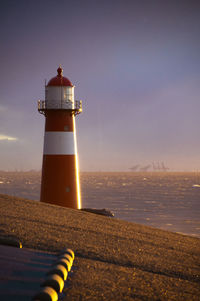 Lighthouse by sea against sky