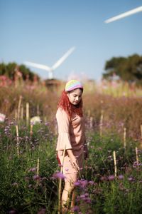 Young woman standing by flowering plants on land