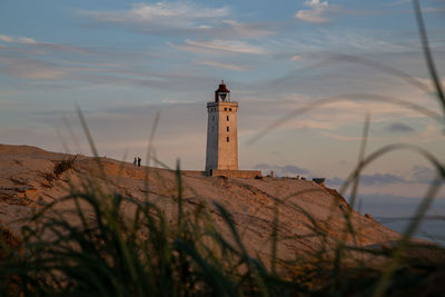 Lighthouse by sea against sky