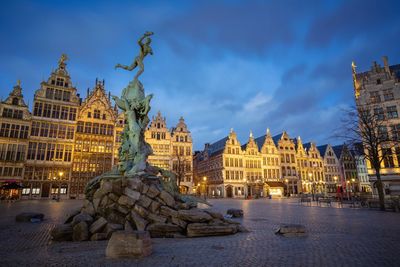 Statue of illuminated buildings against sky at dusk