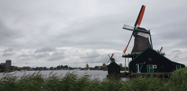 Traditional windmill by building against sky