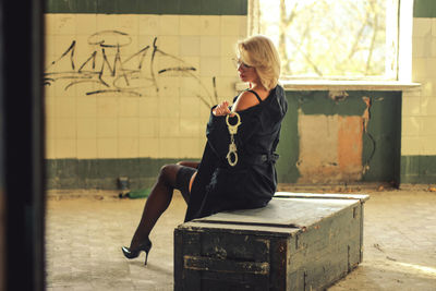 Full length of woman with handcuffs sitting on seat