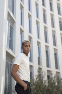Young man standing against building in city