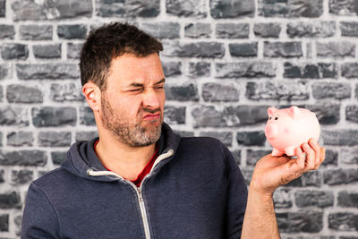 Midsection of man holding camera against wall