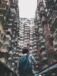 Rear view of man standing amidst buildings in city