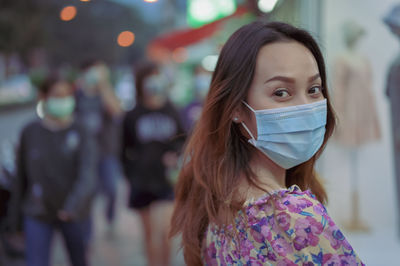 Young women wearing surgical protection mask looking back to camera when her walking onthe street