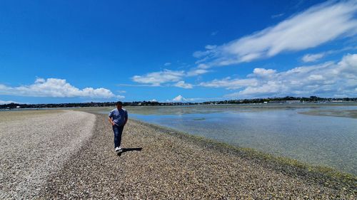 Rear view of man on beach against sky