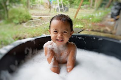 Portrait of cute baby girl sitting in bathtub