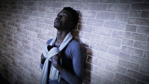 Young woman standing against brick wall