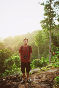 Full length portrait of young man standing against trees