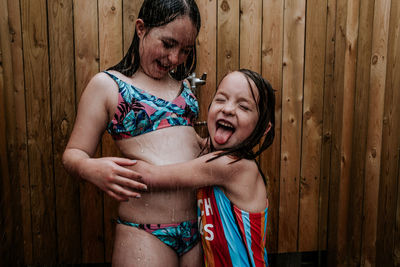 Sisters playing in outdoor shower on a summer day