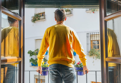 Rear view of man standing by window