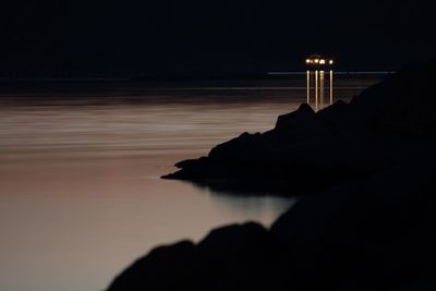 Illuminated boat sailing in river during sunset