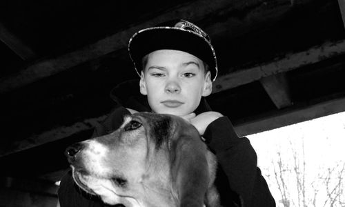 Portrait of boy wearing cap by dog against roof