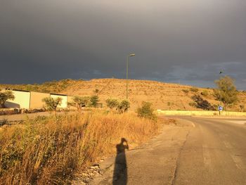 Shadow of person on road against sky