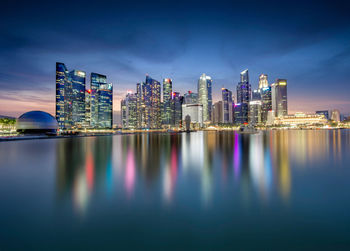 Illuminated buildings by river in city at night