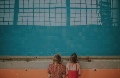 Rear view of women standing by swimming pool