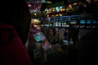 Rear view of woman using smart phone at night