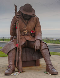 Man sitting on seat by sea against sky