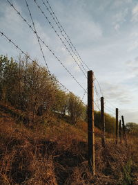 Low angle view of fence on field against sky