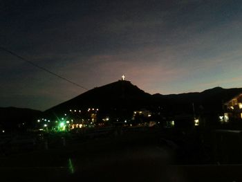 Illuminated street light against sky at night