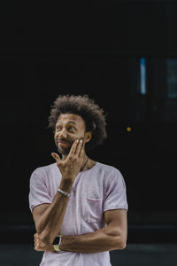 Confused man touching face in front of black wall