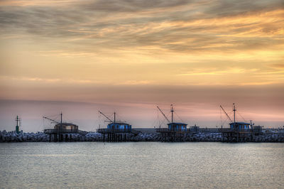 Commercial dock by sea against sky during sunset
