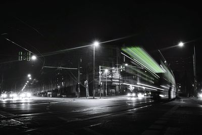 Light trails on illuminated city against sky at night