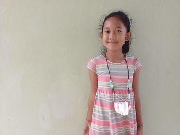 Portrait of young woman standing against wall