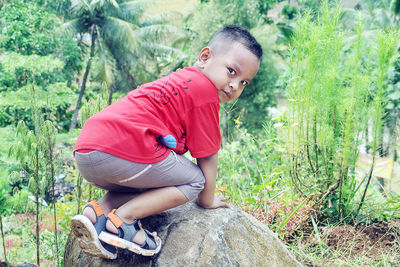 Cute boy looking at camera and climbing rock