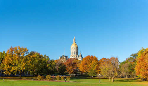 Trees and temple against clear blue sky