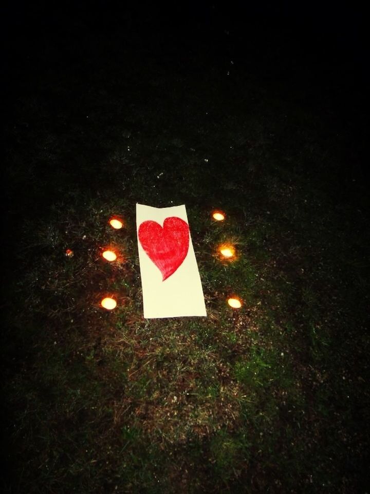 red, high angle view, night, heart shape, no people, close-up, celebration, outdoors, love, copy space, guidance, flag, white color, symbol, star shape, dark, creativity, still life, human representation, studio shot