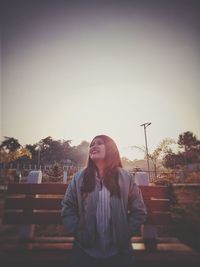 Young woman looking at camera against sky