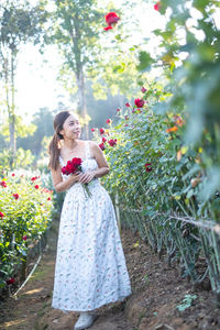 Portrait of young woman standing by plants