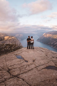 Couple standing and facing each other at cliff at preikestolen, norway during sunset