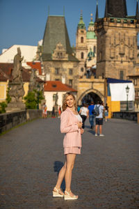 Portrait of woman standing against building in city