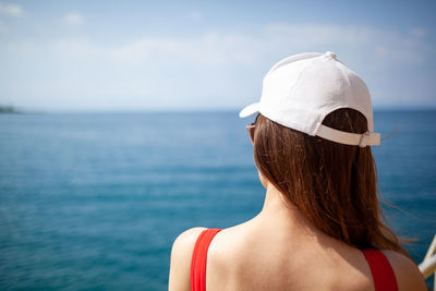 Portrait of young woman looking at sea against sky