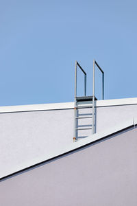 Low angle view of ladder on wall against clear sky