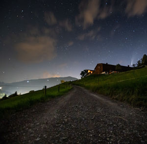 Road amidst field against sky at night