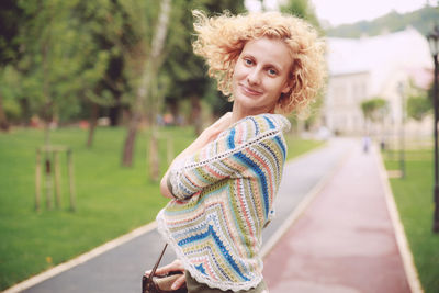 Portrait of woman standing on footpath at park