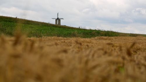 Wheat field by traditional windmill against sky