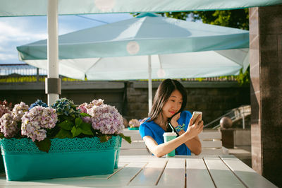 Woman taking selfie while having coffee at outdoor cafe