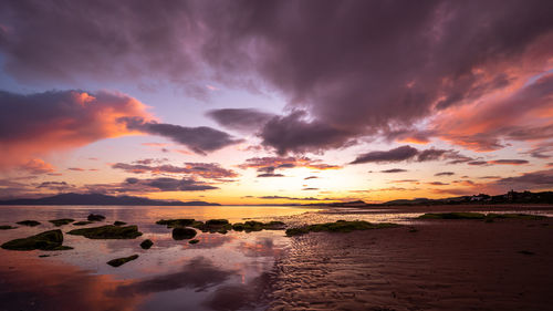 Scenic view of sea against dramatic sky during sunset