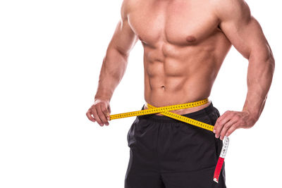Midsection of shirtless man standing against white background