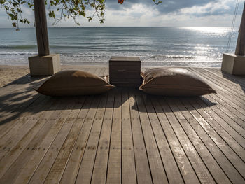 Lounge chairs by swimming pool at beach against sky