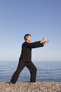 Full length of man doing martial arts at beach