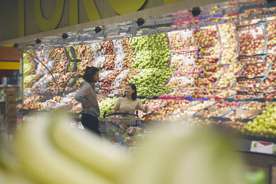 View of couple standing in supermarkets and talking while choosing apples