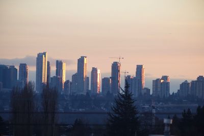 Modern buildings in city against sky during sunset